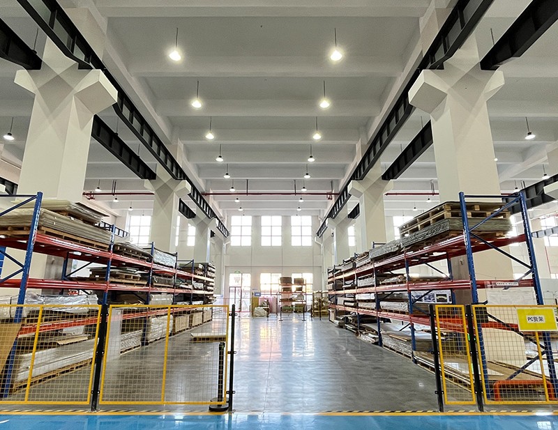 Koridor gudang dengan stok lembaran tersusun di sistem rak